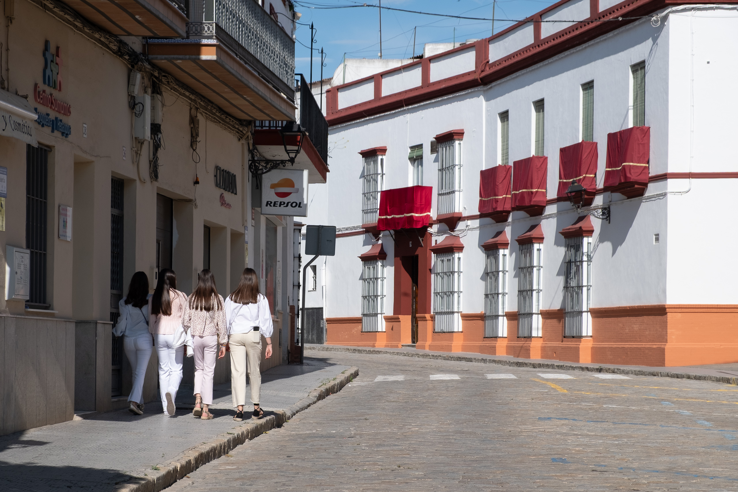 Herausgeputzte junge Frauen – rote Semana-Santa-Dekorationen an den Balkonen
